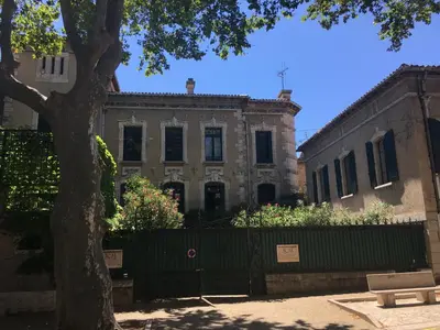 a building with a fence in front of a tree at Château Tallavignes in Fabrezan