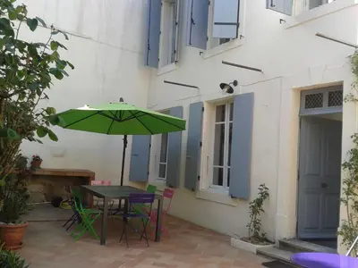a patio with a table and a green umbrella at Chez Clémentine in Montolieu