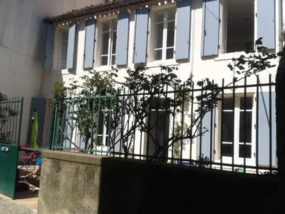 a white house with blue windows and a fence at Chez Clémentine in Montolieu