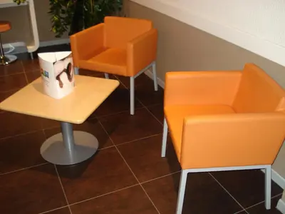 a kitchen with wooden tables and stools in a room at ibis budget Narbonne Sud A9/A61 in Narbonne