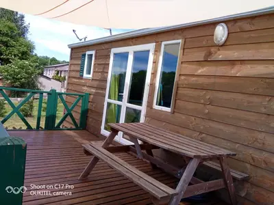 a wooden cabin with a bench on a deck at Les chalets de Bes 