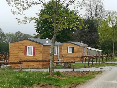 a log cabin with a fence and a tree at Les chalets de Bes 