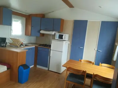 a kitchen with blue cabinets and a table and a white refrigerator at Les chalets de Bes Le Montagnol in Lacombe