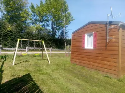 a small shed with a swing set in a yard at Les chalets de Bes Le Montagnol in Lacombe