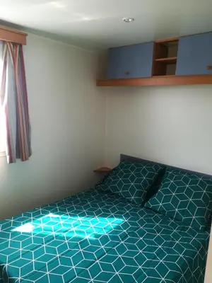 a bedroom with a bed with a blue comforter at Les chalets de Bes Le Montagnol in Lacombe