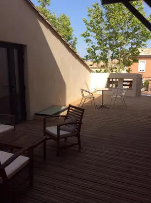 a patio with chairs and a glass table on a building at villa du chai studio pyrénées in Lézignan-Corbières