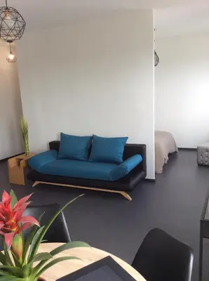 a living room with a blue couch in a room at villa du chai studio pyrénées in Lézignan-Corbières