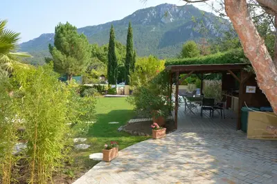 a patio with a table and chairs in a garden at Le Jardin des Gorges in Belvianes-et-Cavirac