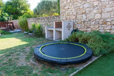 a trampoline in a yard next to a stone wall at La Barbacane in Sigean
