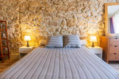 a bed in a room with a stone wall at La Barbacane in Sigean