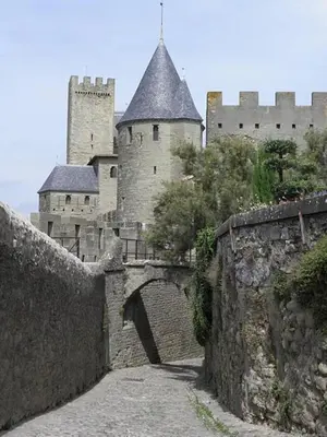 a castle with a stone wall and a bridge at Le Logis des Remparts à l'intérieur de la Cité médiévale, Jardin privé, Parking inclus in Carcassonne