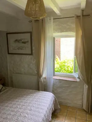a bedroom with a bed and a window at Le Logis des Remparts à l'intérieur de la Cité médiévale, Jardin privé, Parking inclus in Carcassonne
