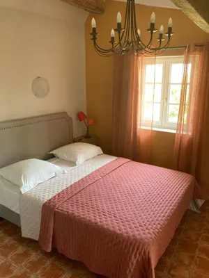 a bedroom with a bed with a pink blanket and a window at Le Logis des Remparts à l'intérieur de la Cité médiévale, Jardin privé, Parking inclus in Carcassonne