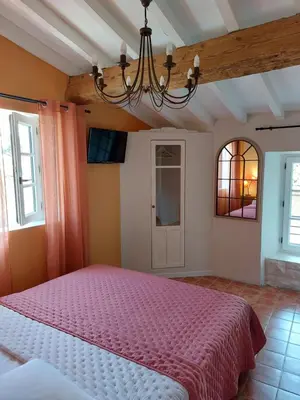 a bedroom with a bed and a chandelier at Le Logis des Remparts à l'intérieur de la Cité médiévale, Jardin privé, Parking inclus in Carcassonne