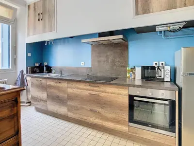 a kitchen with blue walls and wooden cabinets at Apartment La Terasse in Carcassonne