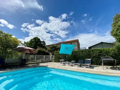 a swimming pool with two chairs and a blue umbrella at Canta aoussel in Moussoulens