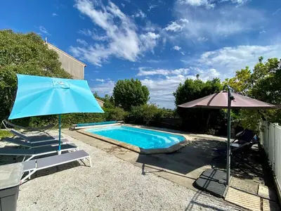 a blue pool with an umbrella and a chair at Canta aoussel in Moussoulens
