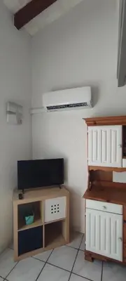 a living room with a tv and a table with a cabinet at Gites Vert à la mer climatisation dans toutes les pièces in Port-la-Nouvelle