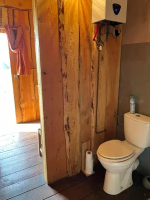 a bathroom with a toilet and a wooden wall at Yourte Mongole Insolite - Gîte Saint Roch in Tuchan