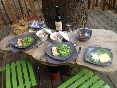 a wooden table with plates of food and a bottle of wine at Cabane Écureuil & Cabane Chevreuil in Fournes-Cabardès