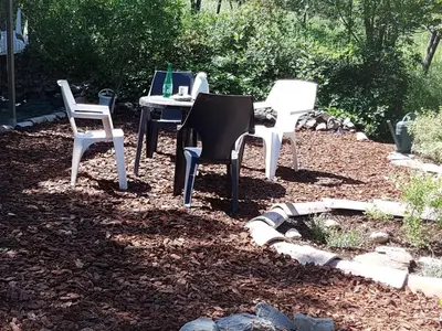 three chairs and a table in a yard at L'Esprit du vallon de Berlou in Berlou