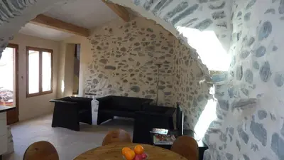 a living room with a table and a stone wall at L'Esprit du vallon de Berlou in Berlou