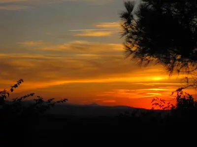 a sunset in the mountains with a tree in the foreground at Belrepayre in Manses