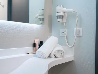a bathroom with a sink and a mirror and towels at ibis budget Narbonne Est in Narbonne