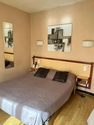 a bedroom with a bed and a desk in it at Hôtel Restaurant Les Arcades in Limoux
