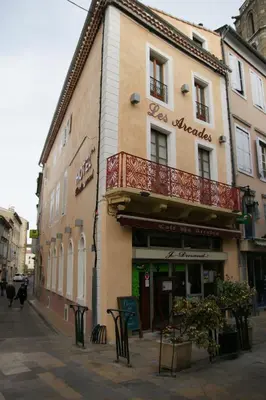 a building with a balcony on the side of a street at Hôtel Restaurant Les Arcades in Limoux