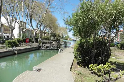 a walkway next to a river with trees and buildings at Escapade Audoise in Sallèles-dʼAude