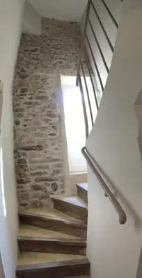 a stairway with a stone wall and wooden stairs at Côté chateau in Carcassonne