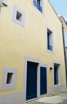 a yellow building with blue doors and windows at Côté chateau in Carcassonne