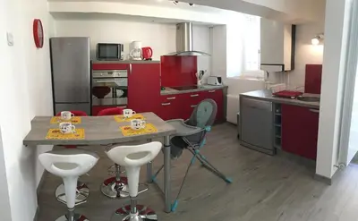 a kitchen with red cabinets and a table with stools at Côté chateau in Carcassonne