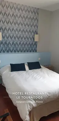 a bedroom with a bed with a blue headboard at Le Tournedos in Lézignan-Corbières