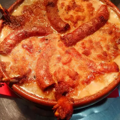a pizza with sausage and cheese on a table at Le Tournedos in Lézignan-Corbières