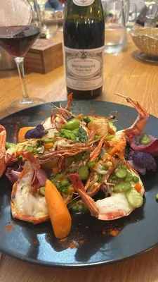 a plate of food with seafood and a bottle of wine at Le Tournedos in Lézignan-Corbières