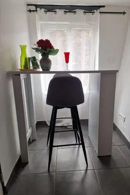 a desk with a chair and a vase of flowers at Le camélia de la mazarié in Saint-Vincent