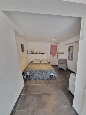 a bedroom with a bed and a tiled floor at Le camélia de la mazarié in Saint-Vincent