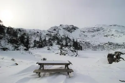 a picnic table in the snow with mountains in the background at Toupinat in Montferrier