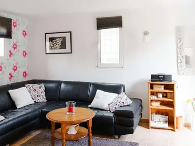 a living room with a black leather couch and a table at CE12 Pavillon 3 pièces 6 couchages proche plage du Grazel - FR-1-409-70 in Gruissan