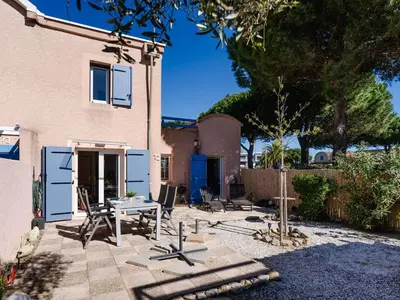 a patio with chairs and a table in front of a house at CE12 Pavillon 3 pièces 6 couchages proche plage du Grazel - FR-1-409-70 in Gruissan
