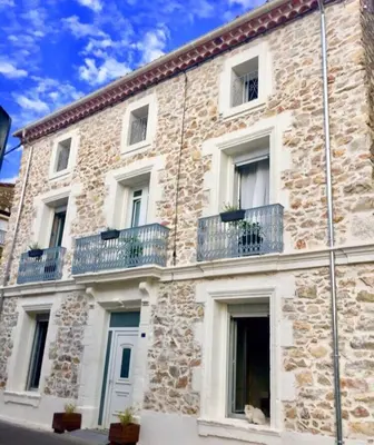 a stone building with balconies and a dog sitting in front of it at Casa Cessenon in Cessenon