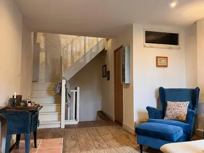 a living room with a blue chair and stairs at Maison Marie in Lagarde