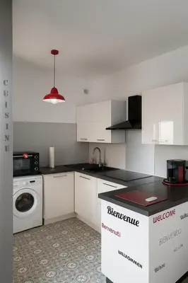 a kitchen with white cabinets and a washer and dryer at Appartement avec Terrasse in Narbonne