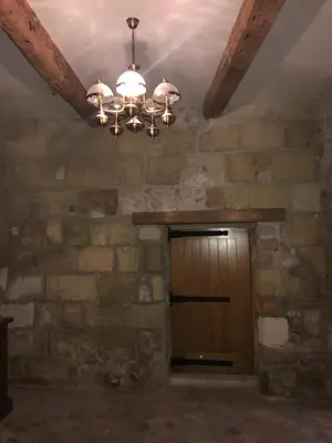 a wooden door in a stone wall with a chandelier at Chambre du couvent in Narbonne