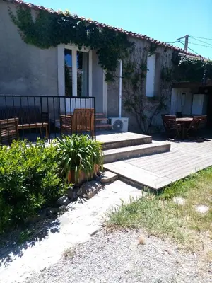 a house with a wooden deck with chairs and a table at Maison du Charron in Azillanet