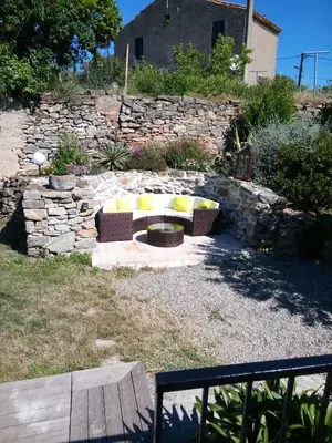 a fire pit in a yard with a stone wall at Maison du Charron in Azillanet