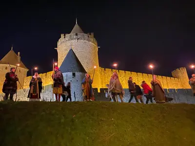 a group of people walking in front of a castle at night at La Rapière in Carcassonne