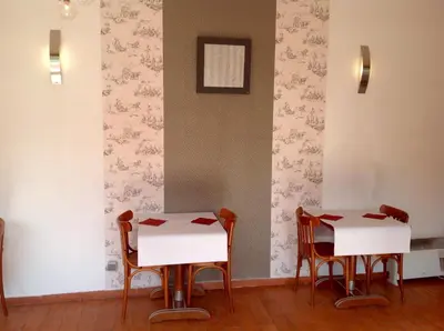 two tables and chairs in a room with wallpaper at La Rapière in Carcassonne